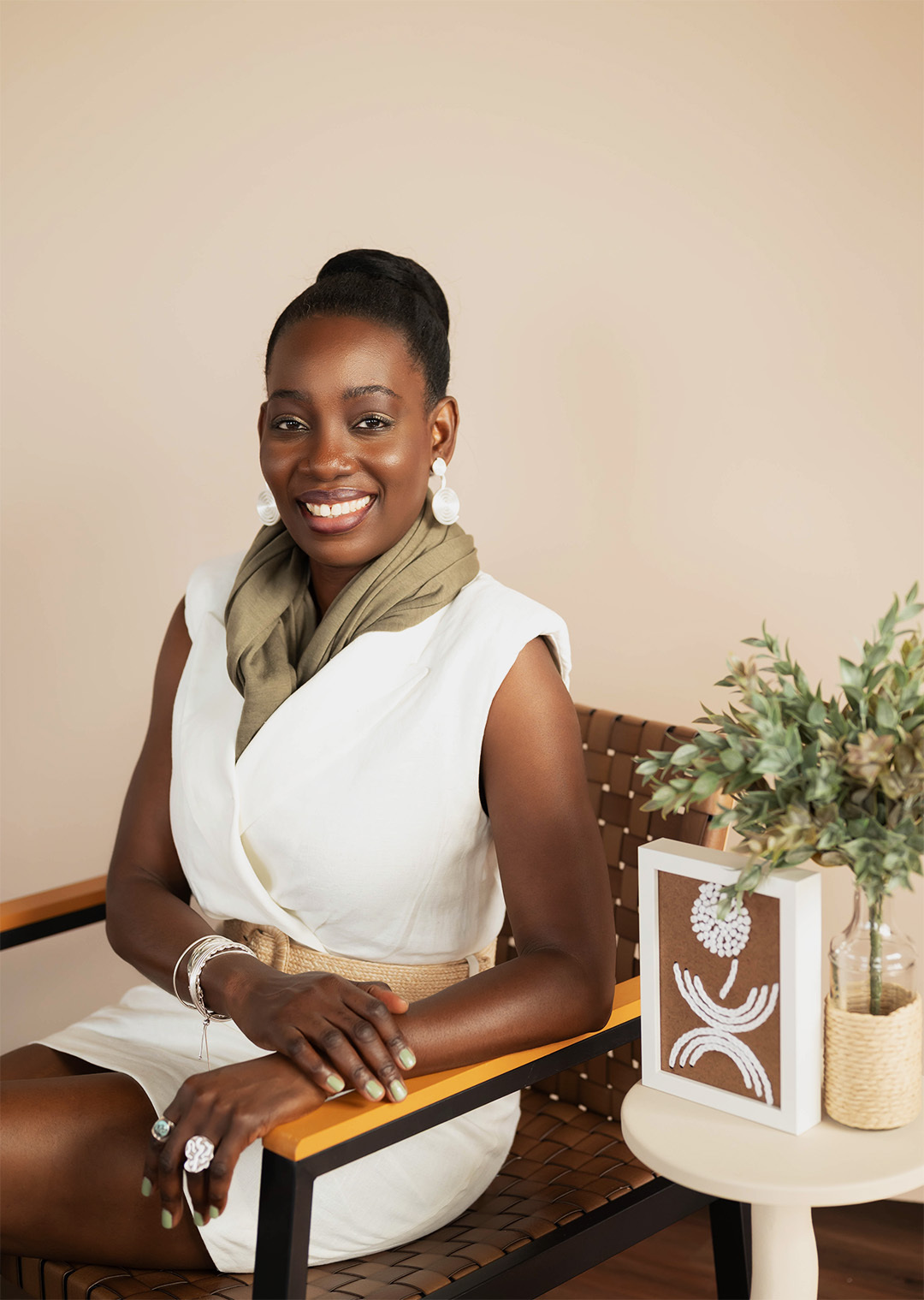 Artist Atinuke Adeleke wearing the igba aye Fumi 3D printed earrings sitting on a chair